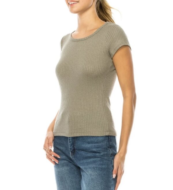 A woman wearing jeans and a beige top.